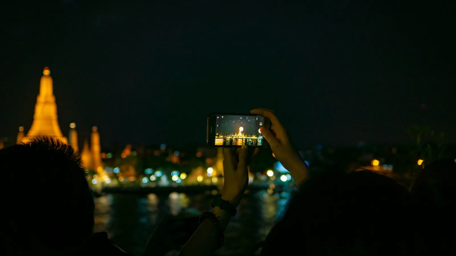 Mobilkamera som fotograferer Wat Arun i Bangkok om kvelden
